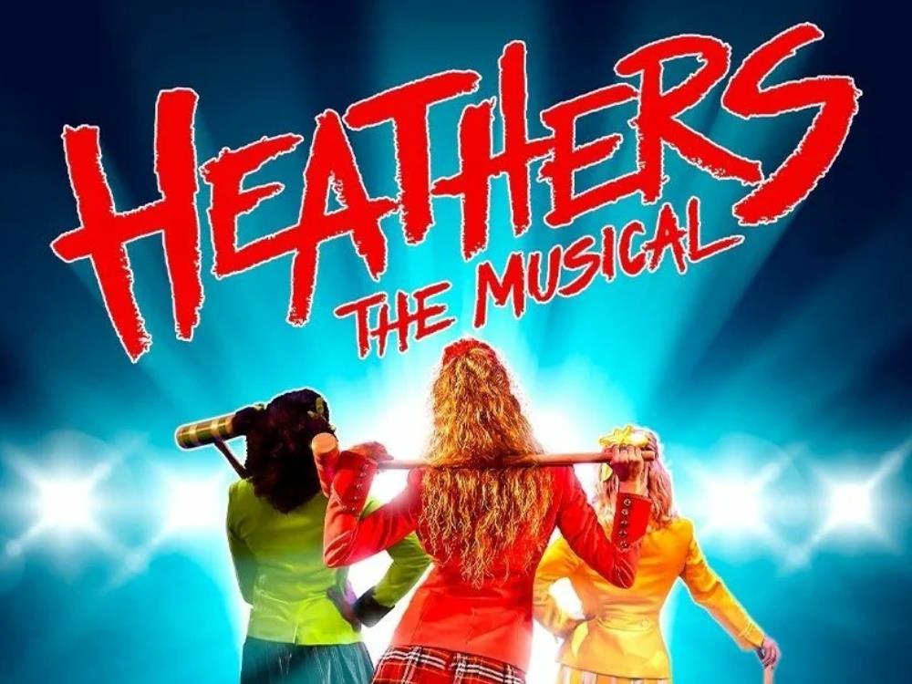 Film Poster for Heathers The Musical. Three school girls in colourful outfits are facing away from the viewer. They are all carrying croquet mallets. The title is written splashily across the top.